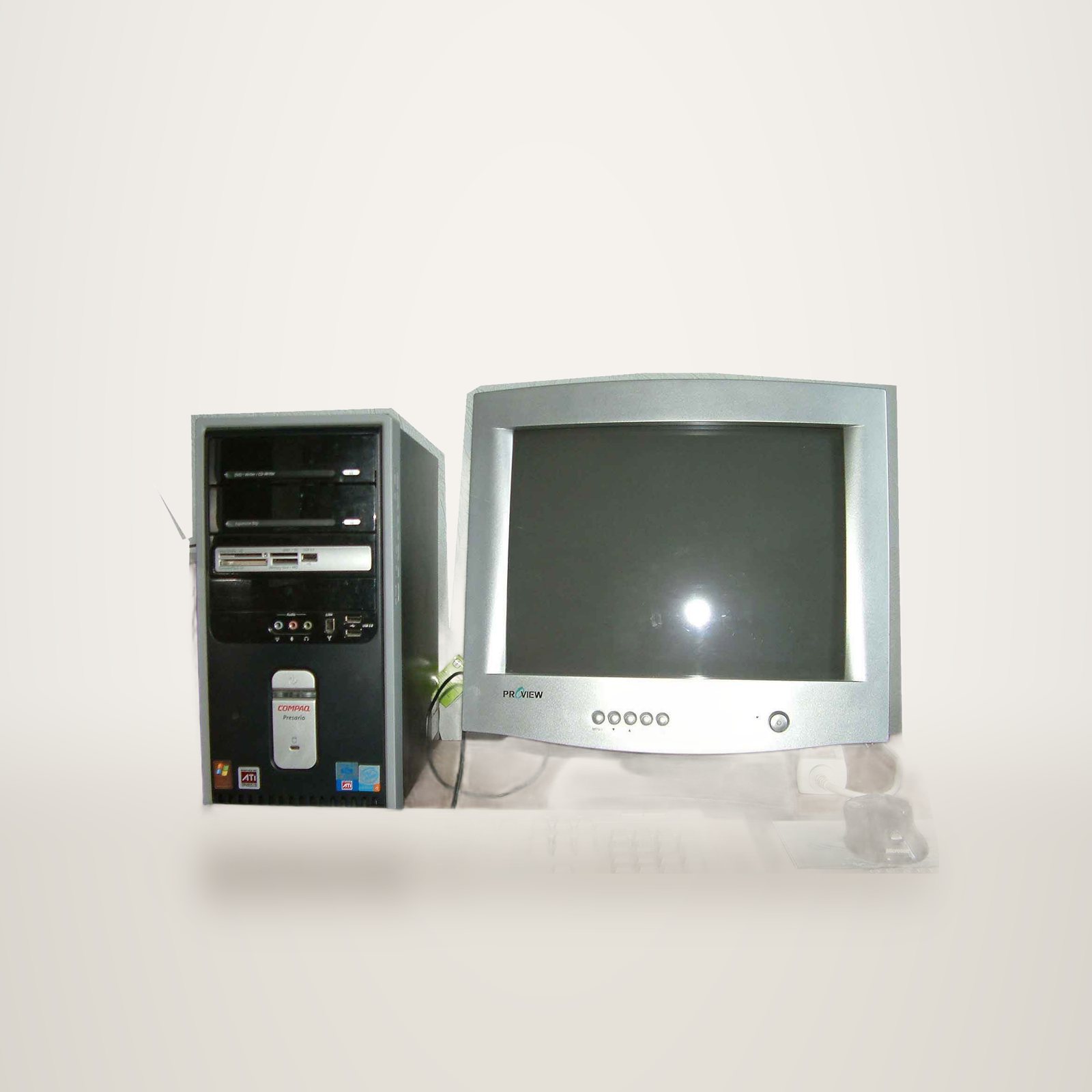 Une tour Compaq Presario, un écran cathodique Proview gris, un clavier et une souris Microsoft posés sur un bureau en bois.
