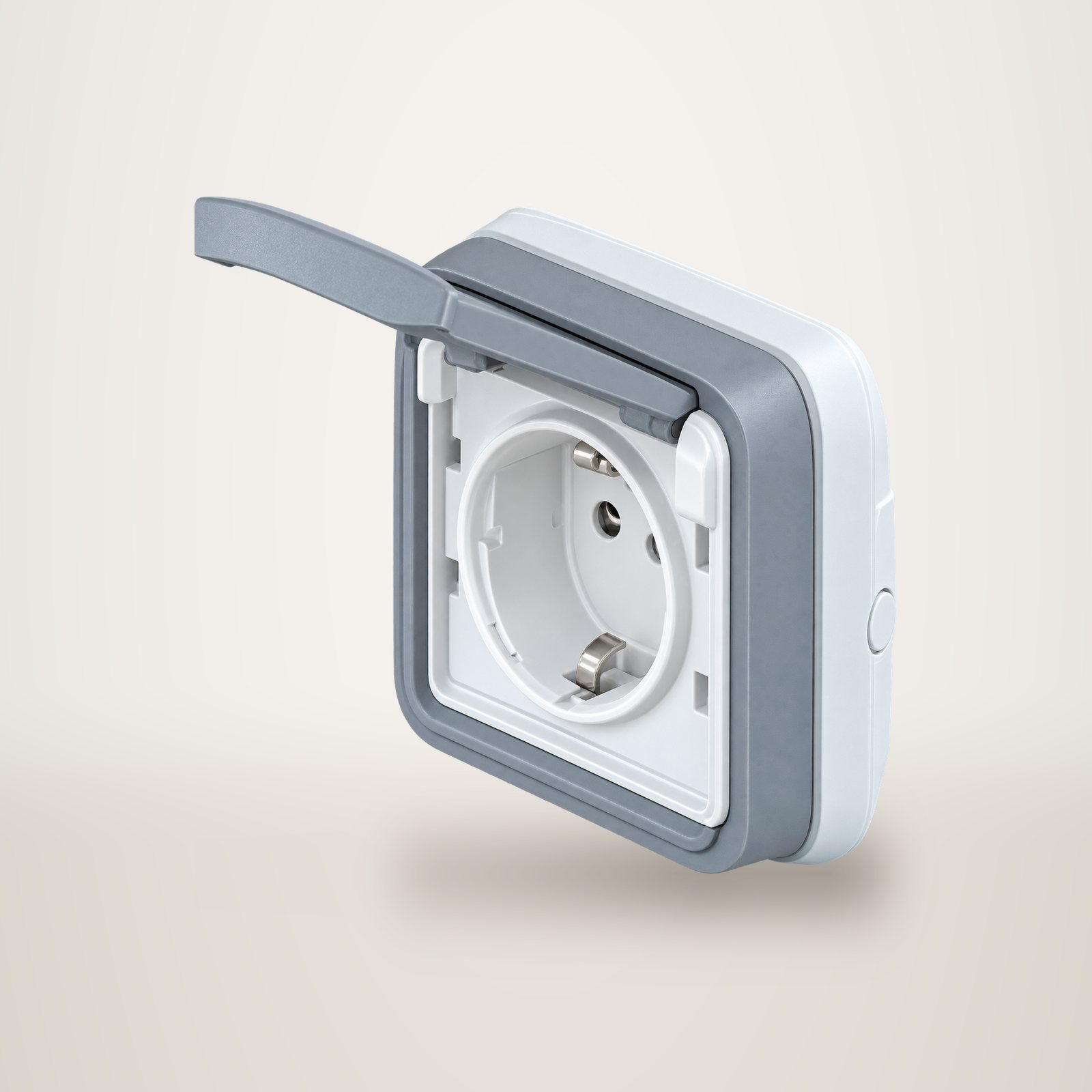 Prise électrique française grise avec son volet de protection transparent ouvert, photographiée sur fond blanc.